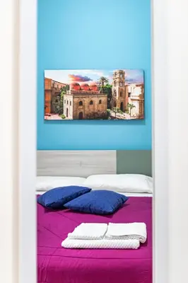 a bedroom with a bed with purple sheets and a painting at Sicily Trinacria House in Palermo