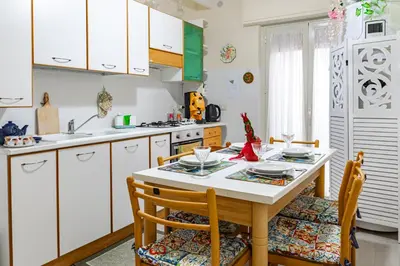 a kitchen with a table and chairs and white cabinets at Sicily Trinacria House in Palermo