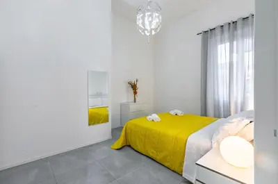a white bedroom with a yellow bed and a mirror at GuestHost - Ballarò Market Cozy Apartments in Palermo
