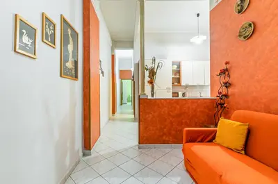 a living room with an orange couch and a kitchen at GuestHost - Ballarò Market Cozy Apartments in Palermo
