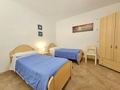 a bedroom with two beds and a chair in it at Costa Mediterranea Holiday Homes in Campofelice di Roccella