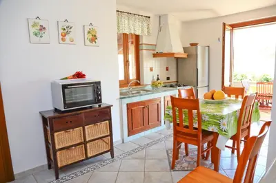a kitchen and dining room with a table and a television at Costa Mediterranea Holiday Homes in Campofelice di Roccella
