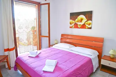 a bedroom with a pink bed with two white towels on it at Costa Mediterranea Holiday Homes in Campofelice di Roccella
