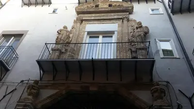 a building with a balcony and statues on it at Casa Vacanze Flavia in Palermo
