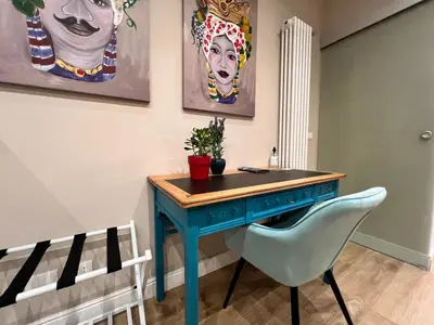 a blue desk in a room with a chair and paintings at Florio House in Palermo