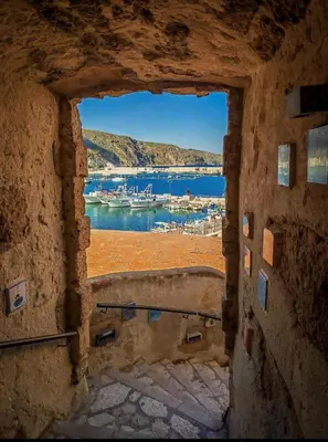 a view of a harbor through a stone window at Casa gli Oleandri in Castellammare del Golfo