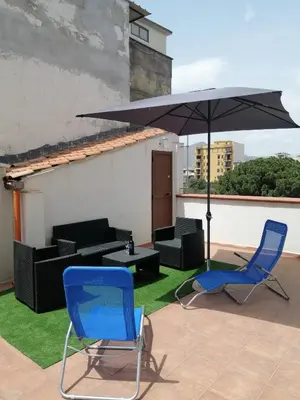 a patio with two blue chairs and an umbrella at Casa del mare Mely in Ficarazzi