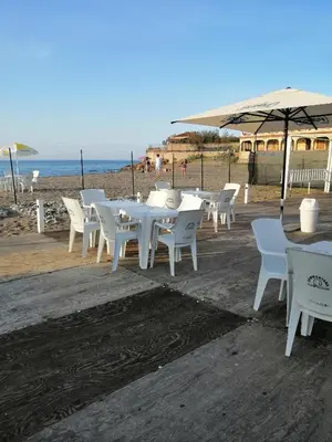 a group of white tables and chairs on the beach at Casa del mare Mely in Ficarazzi