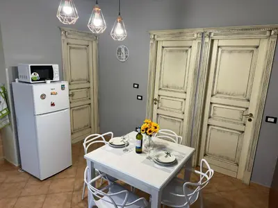 a kitchen with a white table and a refrigerator at Casa del mare Mely in Ficarazzi