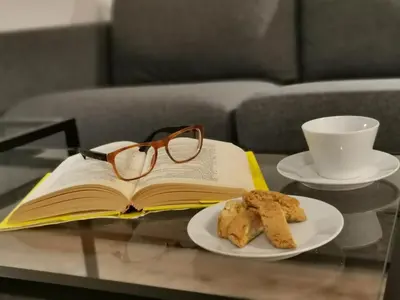 a book and glasses on a table with a plate of cookies at Casarino House Luxury Apartment in Palermo