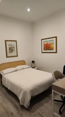 a bedroom with a white bed with two pictures on the wall at Casarino House Luxury Apartment in Palermo
