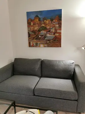 a couch in a living room with a painting on the wall at Casarino House Luxury Apartment in Palermo
