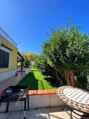 a patio with a table and a green lawn at Villa CLARA in Altavilla Milicia