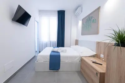 a white bedroom with a bed and a television at Il Cortile Isola Casa Vacanze in Isola delle Femmine