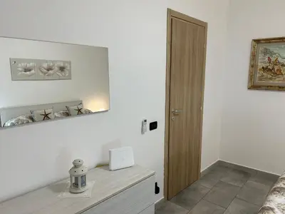a white room with a door and a table with a clock at Ciccio's House in Palermo