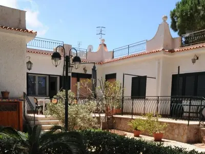 a large white house with a porch and a fence at CASE VACANZA PERLA DEL SUD in San Vito lo Capo