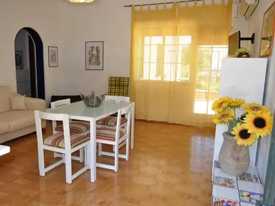 a living room with a table and chairs and a vase with flowers at CASE VACANZA PERLA DEL SUD in San Vito lo Capo