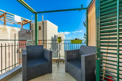a balcony with two chairs and a fence at GuestHost - Sea View Charm - Mondello Apartment with Terrace in Palermo