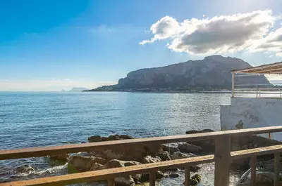a view of a body of water with a mountain at GuestHost - Sea View Charm - Mondello Apartment with Terrace in Palermo