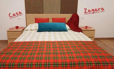 a bedroom with a large bed with a plaid blanket at Palermo case vacanza in Palermo