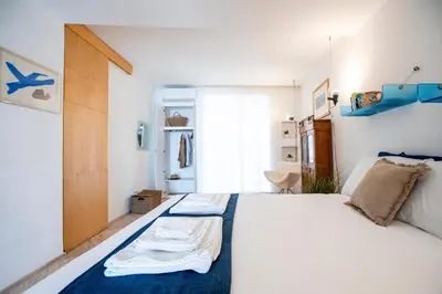 a bedroom with a large white bed with blue accents at Studio Anatólio in Castellammare del Golfo