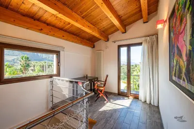 a room with a balcony with a desk and a window at Villa DellAlbero in Alcamo