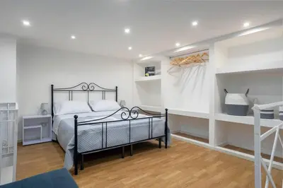 a bedroom with a black bed and white walls at Centro Storico - Casetta al Capo in Palermo