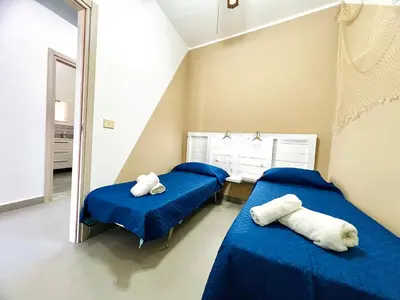 two beds in a room with blue sheets and a mirror at Casa Nonna Anna in Palermo