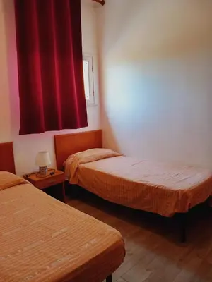 two beds in a room with red curtains at Residence Marino in Balestrate