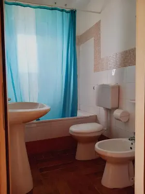a bathroom with a sink and a toilet and a blue shower curtain at Residence Marino in Balestrate