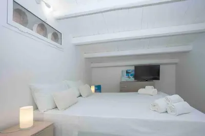 a white bedroom with a large white bed with towels on it at Sky Terrace Mondello Beach house in Palermo