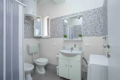 a white bathroom with a toilet and a sink at Sky Terrace Mondello Beach house in Palermo