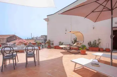 a patio with tables and chairs and an umbrella at Sky Terrace Mondello Beach house in Palermo