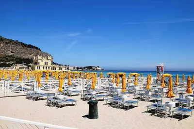 a group of chairs and umbrellas on a beach at Sky Terrace Mondello Beach house in Palermo