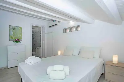 a white bedroom with a large white bed with two white towels at Sky Terrace Mondello Beach house in Palermo