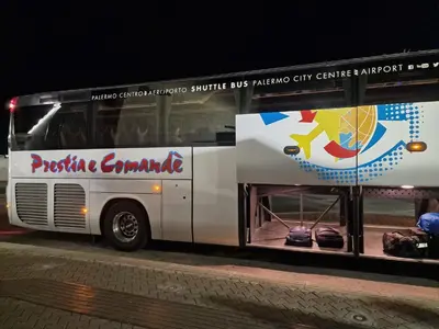 a white bus parked on the street at night at Politeama Dependance in Palermo