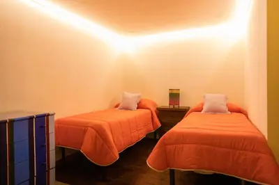 a room with two beds with orange sheets at Hola House alla Magione in Palermo