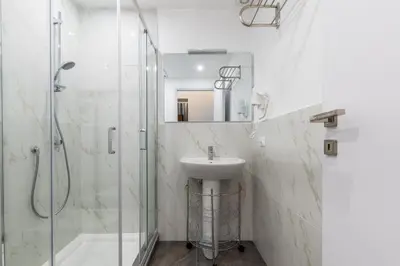 a white bathroom with a sink and a shower at Palazzo Falcone Apartments in Palermo