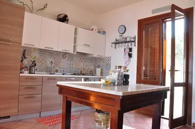 a kitchen with white cabinets and a table in it at B&B Tre Giummare in Scopello