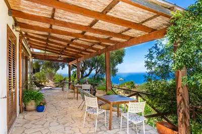 a patio with a table and chairs under a wooden pergola at B&B Tre Giummare in Scopello