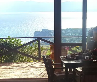 a table with chairs and a view of the ocean at B&B Tre Giummare in Scopello