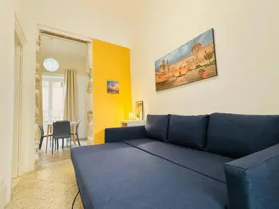 a living room with a blue couch and a dining room at Calamari37 in Palermo