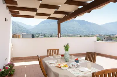 a table on a balcony with a view of mountains at Casa vacanze near airport in Cinisi