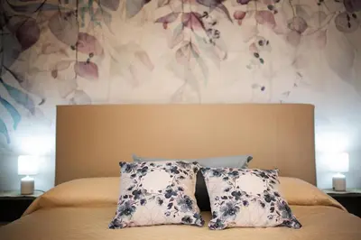 a bed with two pillows and a floral wall at Casa vacanze near airport in Cinisi