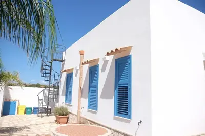 a white house with blue shutters and a palm tree at Villa Indipendente Tranquillità e Relax in San Vito lo Capo