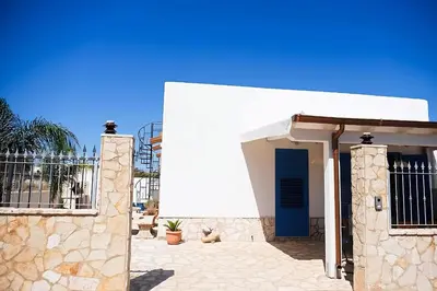 a white house with a blue door on a patio at Villa Indipendente Tranquillità e Relax in San Vito lo Capo