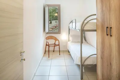 a small room with a bunk bed and a chair at Capo Zafferano Apartments in Santa Flavia
