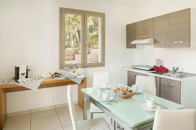 a kitchen with a table and chairs and a counter at Capo Zafferano Apartments in Santa Flavia