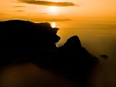 an island in the ocean at sunset at Capo Zafferano Apartments in Santa Flavia