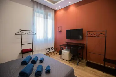 a bedroom with a bed and a television and a desk at Maison La Lumia in Palermo